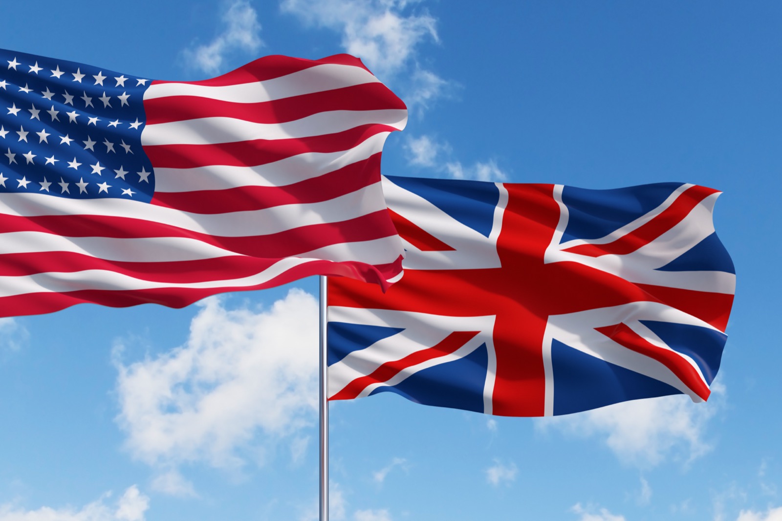 United States flag and United Kingdom flag blowing in the wind together.